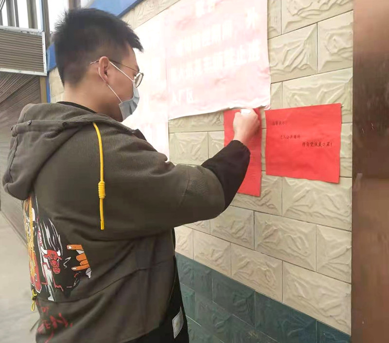 图为单元长在人员密集场所张贴疫情防控宣传单.jpg