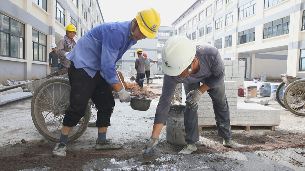 图为工人师傅正在桐城经开区实验学校项目小学部教学楼进行地砖铺设工作.jpg