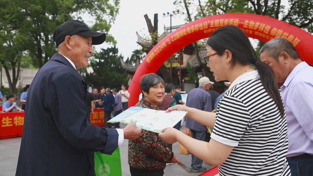 图为现场工作人员正在向过往市民发放宣传材料，讲解生物多样性知识。.jpg
