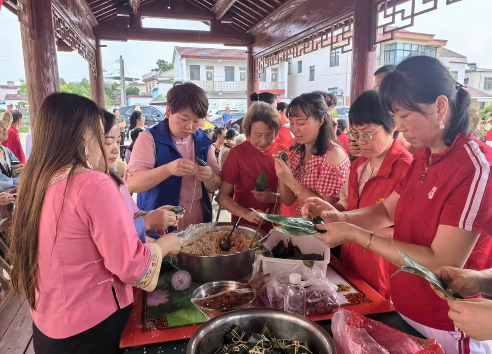 图为村民和志愿者们共同包粽子。.jpg