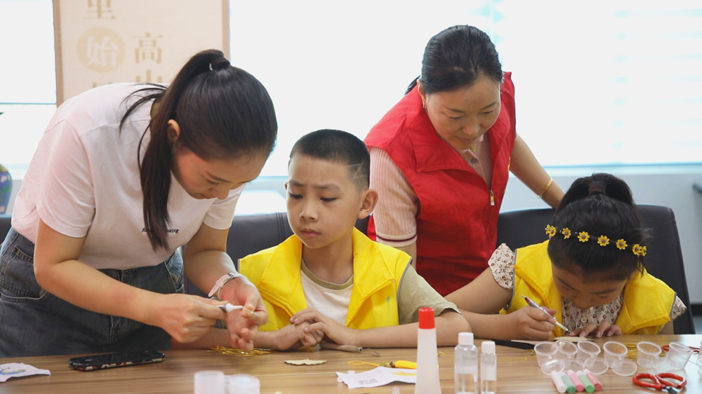 图为孩子们正在家长和社区志愿者的帮助下开展掐丝珐琅手工制作.jpg