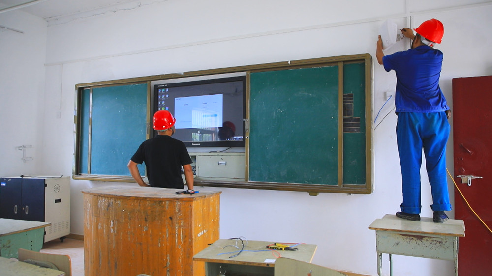 图为高桥中心小学内技术人员正在调试新安装的班班通教学一体机.jpg