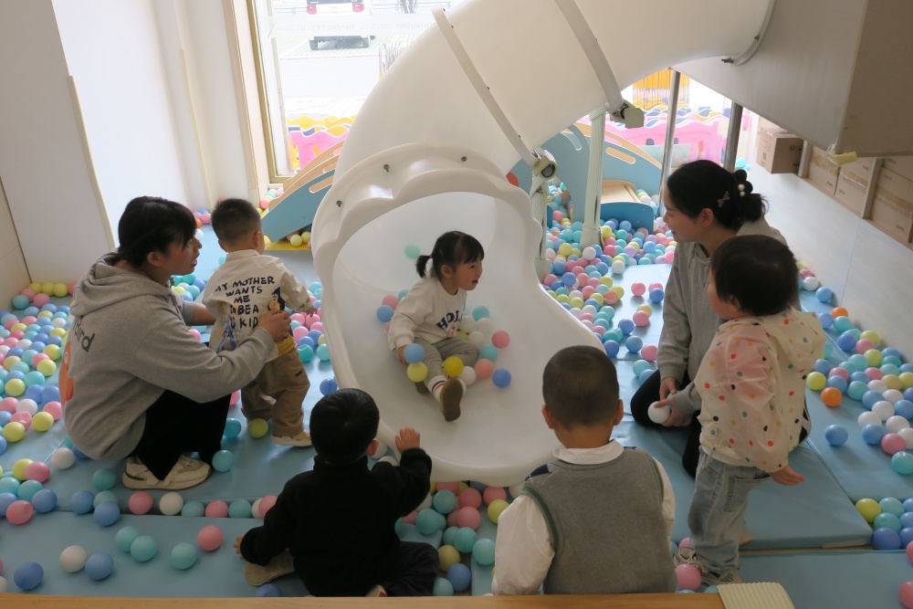 托育中心内幼师和保育员带着小朋友们在游戏区玩耍.JPG