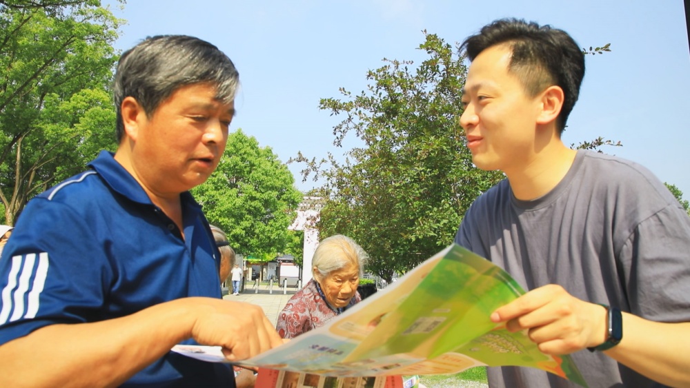 /uploads/image/2025/05/19/26be03f324abe4eac42adf98c8bd6d23.jpg 图为工作人员正在为过往游客介绍桐城市旅游导览图.jpg