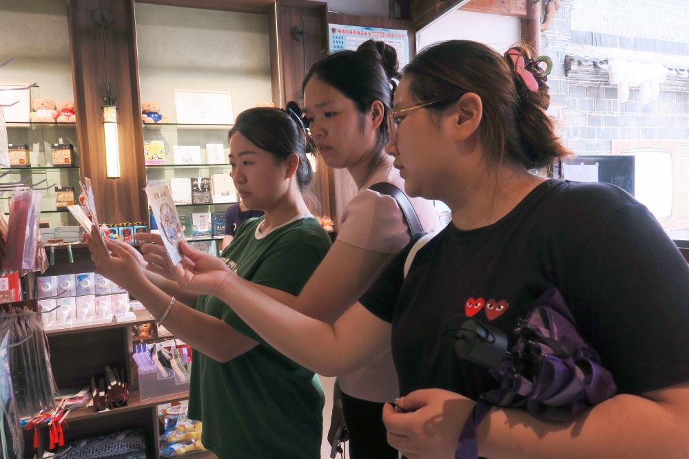 /uploads/image/2025/08/05/1be5d1962da4e58eb0f2f1d3f22a295f.jpg 人世间时光小院内游客正在挑选冰箱贴.jpg