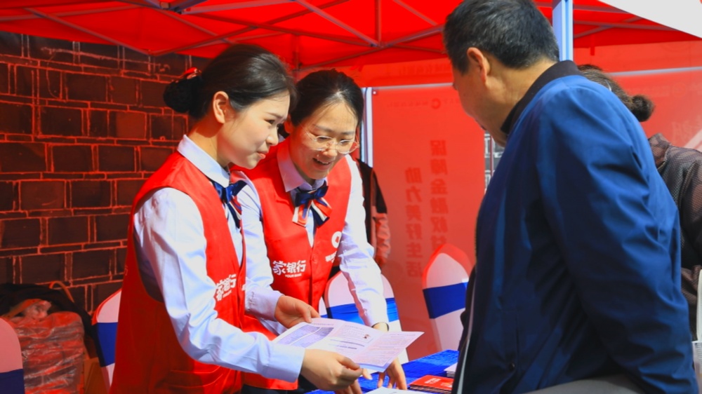 图为现场工作人员向过往市民和游客宣传金融知识.jpg